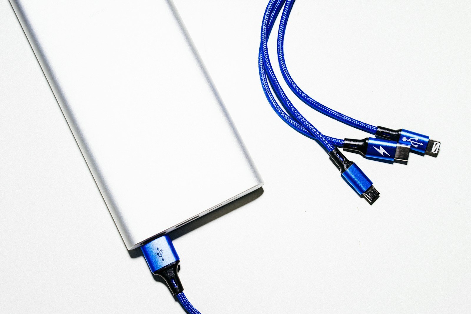 Silver power bank connected to a blue USB cable with several charging connectors