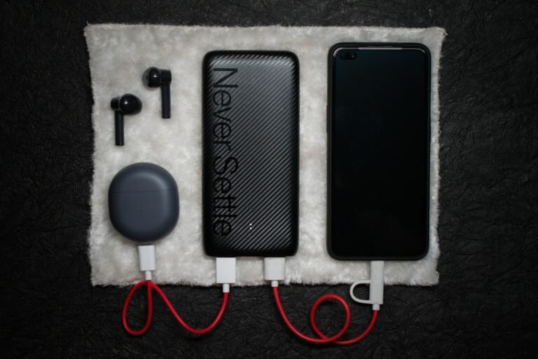 Black power bank connected by USB cables to a phone and an earbud charging case