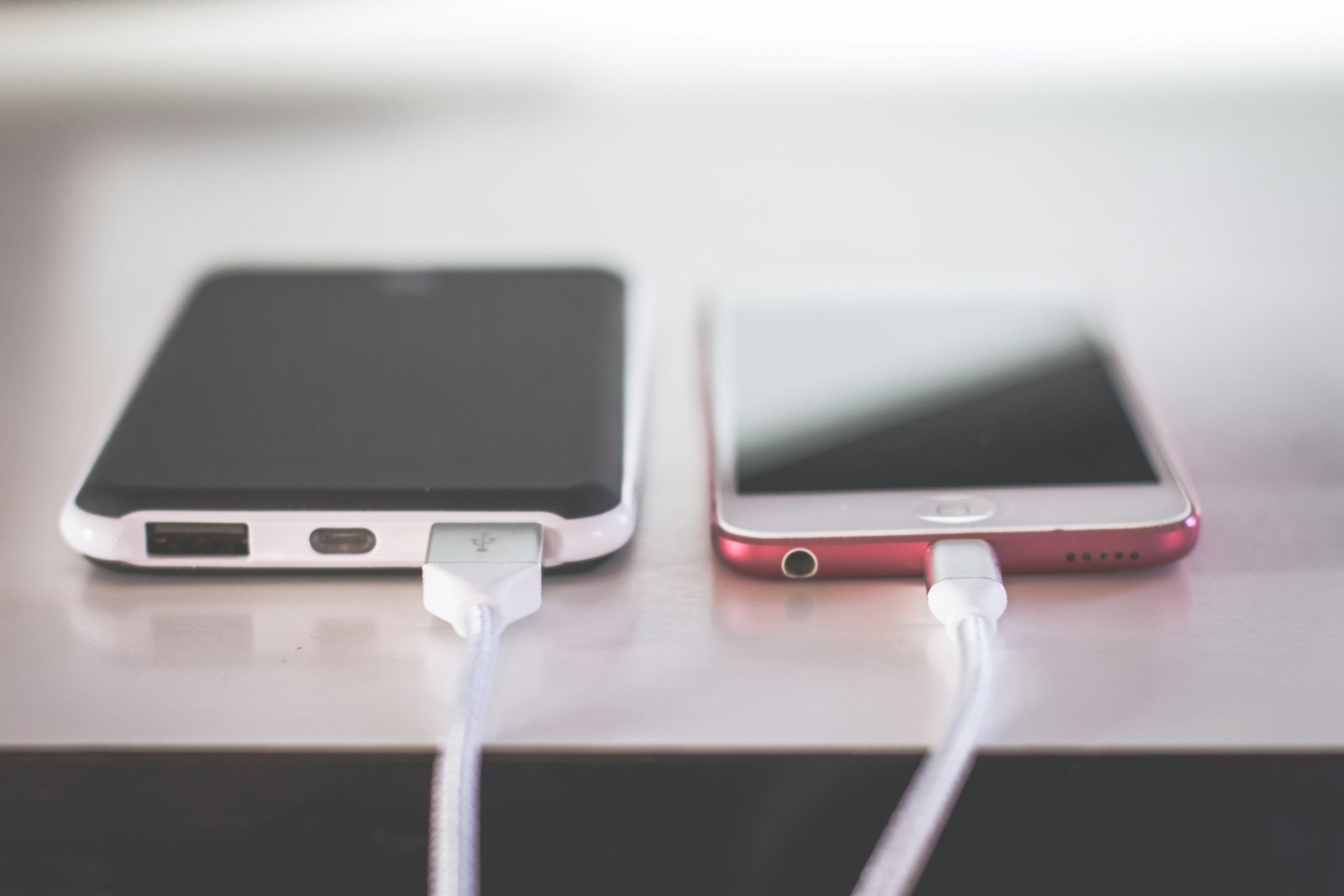 Portable USB battery pack beside a smartphone with charging cables connected