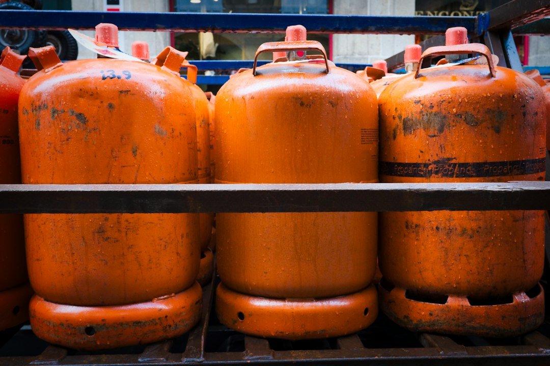 Orange Propane Tanks Stacked on Metal Rack in City Setting