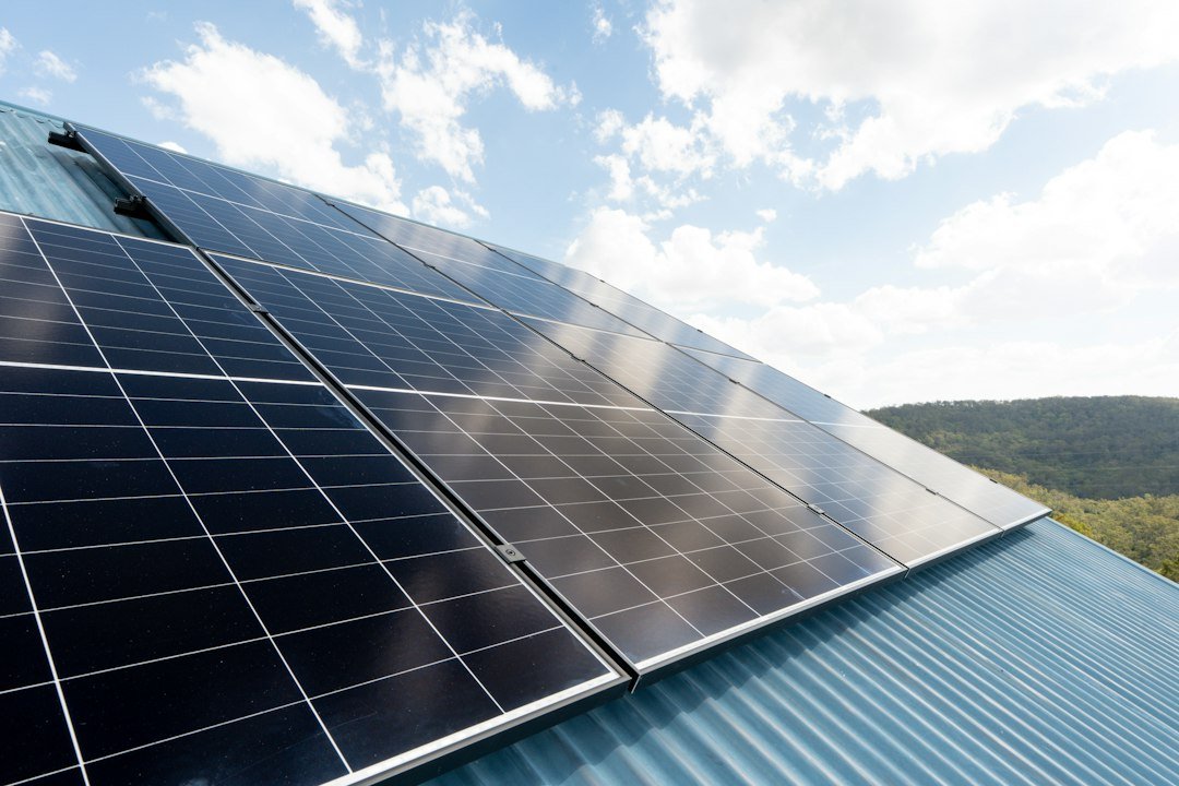 Solar panels on a metal roof under a partly cloudy sky