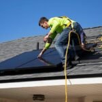 An installer working on solar panels on a house roof