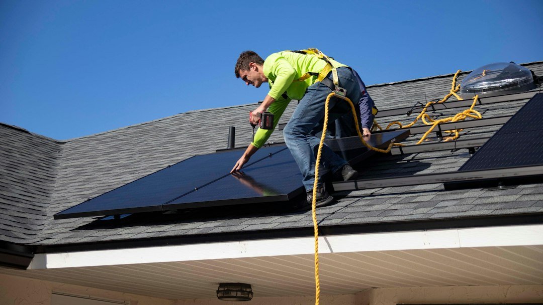 An installer working on solar panels on a house roof