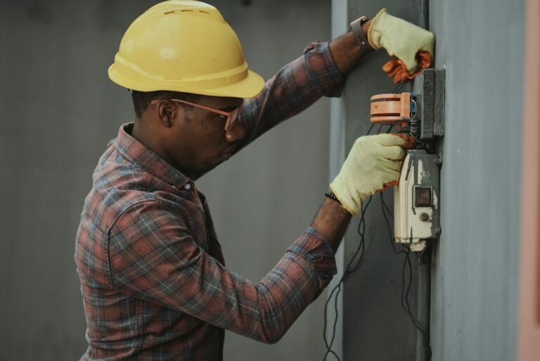 Electrician wearing a hard hat works on an electrical panel